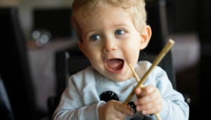 Lansing Kids Eat Free Baby boy sitting in high chair and plays with chopsticks at chinese restaurant.