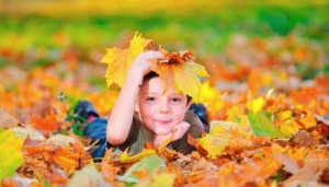 Fall Bucket List Lansing Family Fun Kid in Leaves_header