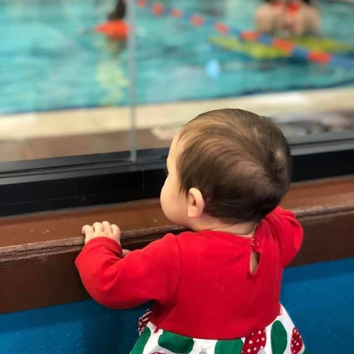 Sister looking through the glass at sisters class Goldfish-Swim-School