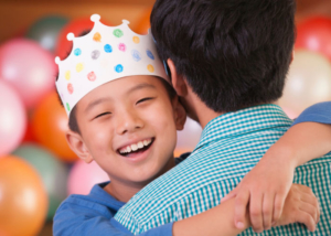 Kid hugging dad with party hat on birthday-parties-Lansing-(1)