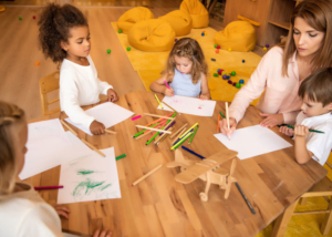 Preschool-Guide-Kids-at-table-coloring-with-teacher-feature