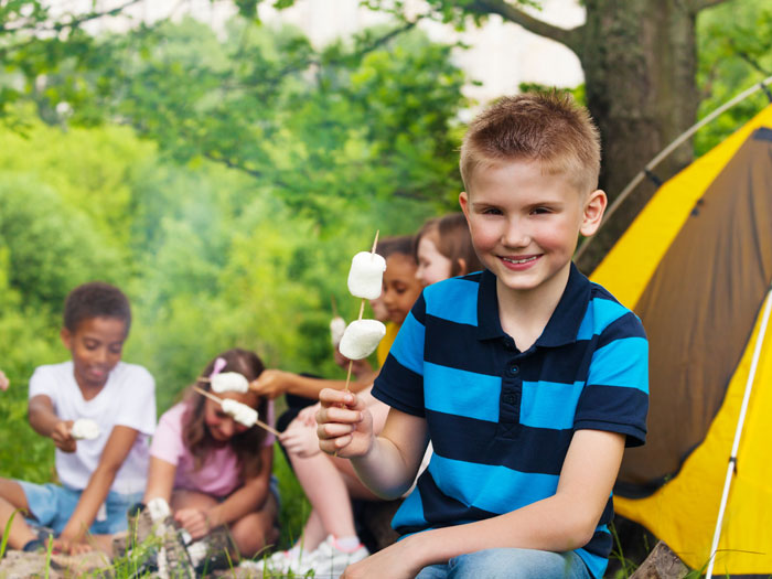Overnight-camps kids roasting marshmallows at camp site Overnight-camps kids roasting marshmallows at camp site