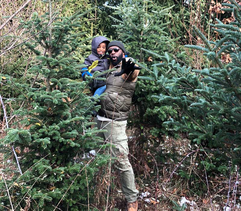 Christmas tree farms feature image boy and dad picking out a tree together