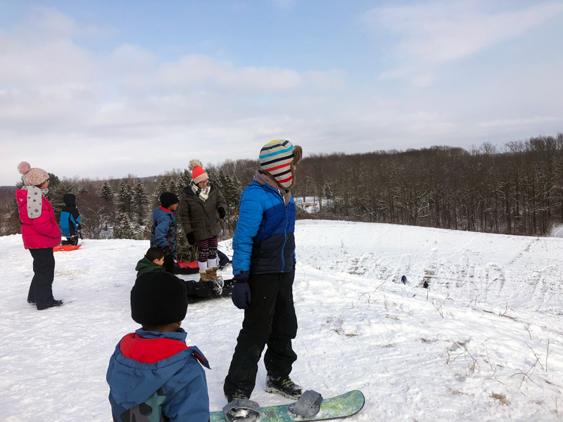 Winter-activities-kids-sledding-and-snow-boarding-down-granger-hill