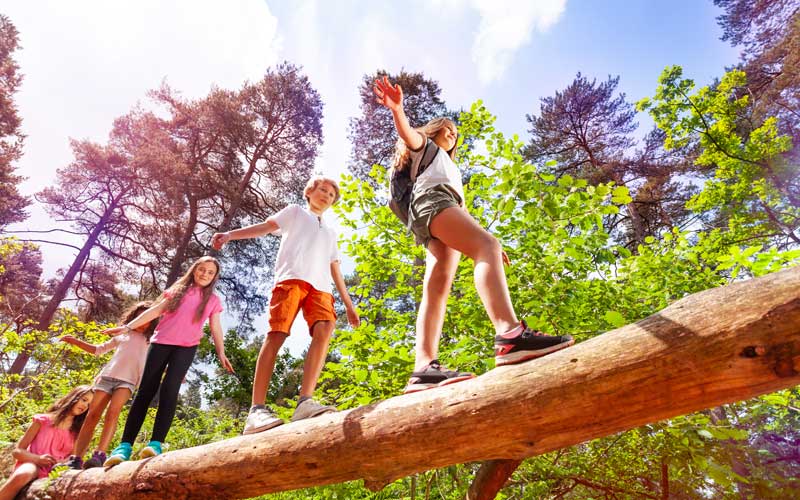 Kids-walking-on-a-log-together-summer-camp